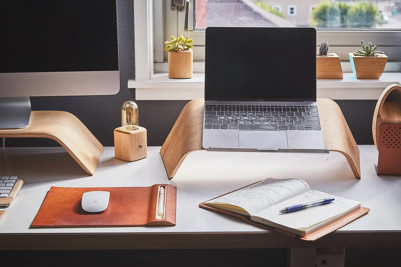 A tidy consultant's desk with laptop and notebook by a window